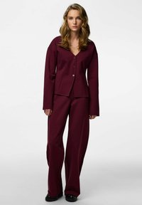 Bordowy komplet składający się z zapinanego na guziki topu z dekoltem w serek i długich rękawów oraz spodni z szerokimi nogawkami. Gładka faktura i minimalistyczny design.