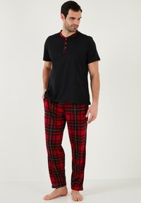 Heren slaapkleding set met een zwart shirt met korte mouwen en rode knoopaccenten, en een rode geruite broek met zwart-witte lijnen.