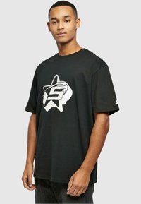 Sort bomulds T-shirt med et stort hvidt stjerne logo med et 'S' i midten. Korte ærmer, afslappet pasform og rund halsudskæring.