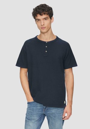 T-shirt à manches courtes bleu marine en tissu doux, avec un col rond et une patte de boutonnage à trois boutons ; présenté avec un léger détail de poche poitrine.