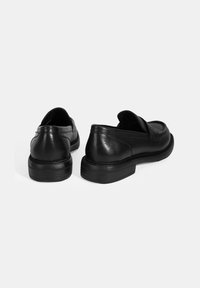 Zwarte leren loafers met een lage, geribbelde zool. Beschikt over een ronde neus en minimale stiksels op het bovenwerk. Schoon, glad oppervlak.