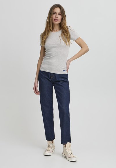 Světle šedé, úzké tričko s krátkým rukávem, v kombinaci s tmavě modrými džíny rovného střihu a béžovými vysokými teniskami.