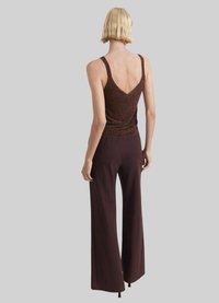 Top marron sans manches avec un dos en V et un subtil éclat, accompagné d'un pantalon large marron. Texture lisse et coupe décontractée.