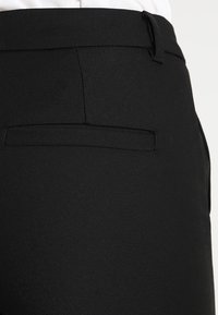 Černé kalhoty s přiléhavým střihem, elegantní design, hladká textilie a jedno zadní kapsa s jemným švy.