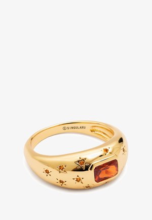 Goldring mit einem rechteckigen orangefarbenen Schmuckstein und sternförmigen Akzenten. Glatte Oberfläche mit einem abgerundeten Band. Markenlogo innen.