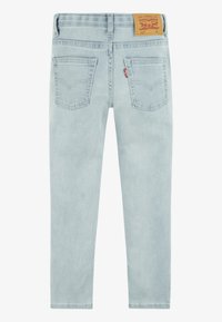 Jeans in denim azzurro chiaro con un design fitted. Presentano due tasche posteriori, cuciture discrete e un'etichetta in pelle beige sulla vita.