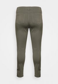 Jeans ajustados de color verde oliva con una textura suave, cintura de altura media y dos bolsillos traseros. Largo hasta el tobillo con detalles de costura mínimos.