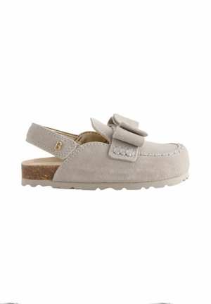 Beige suede moccasin with a bow detail, open back with adjustable strap, and textured sole for casual wear.