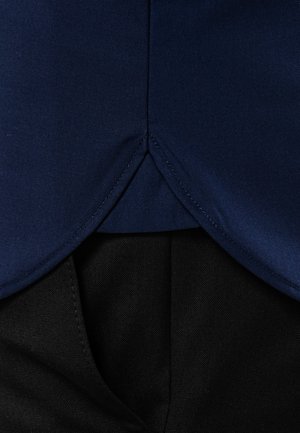 Marineblaue Stoff mit einer glatten Textur, maßgeschneidert im Design eines Hemdes, mit einem abgerundeten unteren Saum, der über schwarzem Stoff liegt.