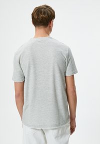 Lichtgrijs kortemouwen t-shirt gemaakt van textuurstof met een ronde halslijn en een losse pasvorm, weergegeven vanaf de achterkant.