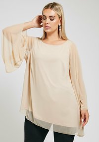 Beige, genomskinlig blus med långa, utsvängda ärmar och rundad halsringning. Lätt material med en flödande form och en fåll som är djupare åt sidorna.