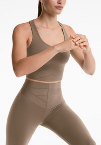 Bruine sportbeha en hoge taille legging gemaakt van een gladde stof met geometrische stiksels en textuuraccenten voor extra ondersteuning.