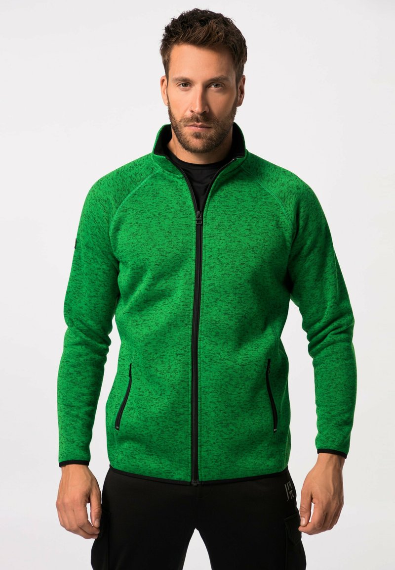 Chaqueta de forro polar verde con cierre de cremallera, diseño texturizado, acentos negros y bolsillos laterales. Ajustada, con cuello alto y mangas largas.