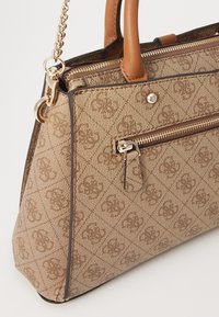 Borsa beige con un motivo testurizzato, dettagli in pelle marrone, una tracolla in catena dorata e una tasca frontale con zip. Presenta una forma strutturata.