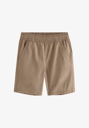 Dreng iført stråhat, t-shirt med tropisk print, brune shorts, sokker med tukan-mønster og beige sko, stående mod ensfarvet baggrund.