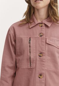 Roza denim jakna z ojačanim ovratnikom, sprednjimi gumbi, žepom na zadrgo na prsih in enim stranskim nalepnim žepom.