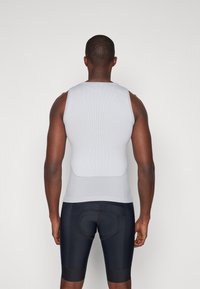 Männer graues, geripptes Tanktop mit taillierter Passform, kombiniert mit schwarzen Fahrradhosen mit gepolstertem Einsatz und kontrastierenden Nähten.