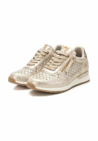 Zapatillas de deporte metálicas en color beige con diseño perforado, cierre de cordones, cremallera lateral, cuello acolchado y suela de goma texturizada.