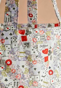 Barvna torba s cvetnimi in igrami navdihanimi vzorci, vključno s kockami, igralnimi kartami in šahovsko figuro. Vidna je tudi oznaka Cath Kidston.