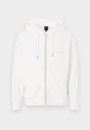 Sudadera con capucha blanca con cremallera, hecha de tela suave, con capucha ajustable mediante cordón, puños acanalados y un pequeño parche con logo en el pecho.
