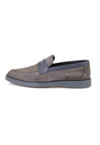 Des chaussures à enfiler en daim gris avec une bande d'accent en cuir gris plus foncé. Elles sont dotées d'une semelle en caoutchouc plate et d'un design à bout arrondi.