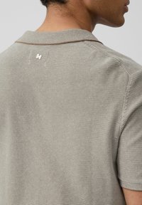 Beżowa polo z paskami, z kołnierzykiem, krótkimi rękawami oraz metalicznym logo z tyłu. Teksturalna dzianina.