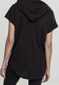 Svart kortärmad hoodie med rundad nederkant och dragsko i huvan, tillverkad av ett mjukt tyg med en avslappnad passform.