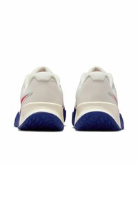 Scarpe sportive bianche con una parte superiore in mesh testurizzato, dettagli rossi e blu, e una suola in gomma blu ben visibile. Presentano un design del tallone imbottito.