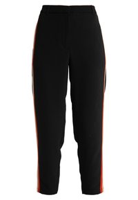 Czarne zwężane spodnie z czerwonym i beżowym pionowym paskiem biegnącym po zewnętrznej stronie każdej nogawki, z paskami na pasek w talii.