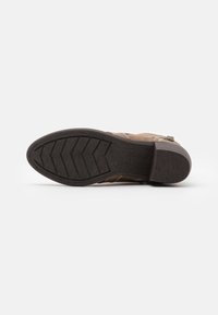 Botte en cuir marron avec un dessus texturé, semelle en caoutchouc présentant un motif en chevrons et détail de fermeture éclair sur le côté pour un enfilage facile.