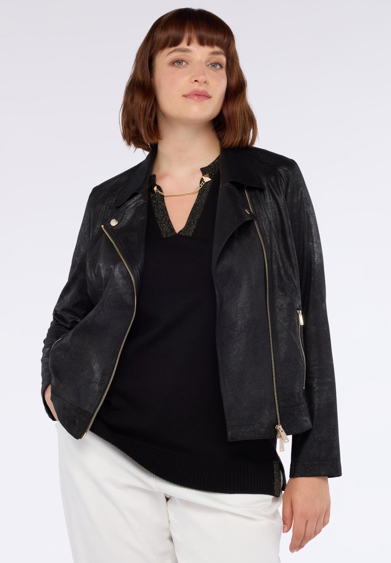 Svart faux läder bikerjacka med en strukturerad krage, asymmetrisk dragkedja och detaljer i metallbeslag. Bärs över en svart topp.