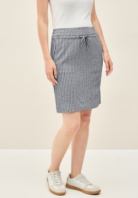Gestreepte blauw-witte knielange rok met elastische taille en koord, gemaakt van een lichte stof, gecombineerd met witte sneakers.