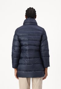 Navy puffer jacket with a high collar, quilted design, and “HILFIGER” branding at the collar. Long sleeves, smooth texture, knee-length.