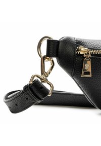 Angolo di borsa in pelle nera testurizzata con cerniera dorata e fibbia che collega la tracolla regolabile all’anello dorato su sfondo bianco.