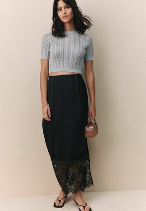 Hallide tumehall villane lühikeste varrukatega crop top, mille juurde on sobitatud pikk must seelik, millel on pitsäär. Komplektis on väike roosa kuldne käekott.