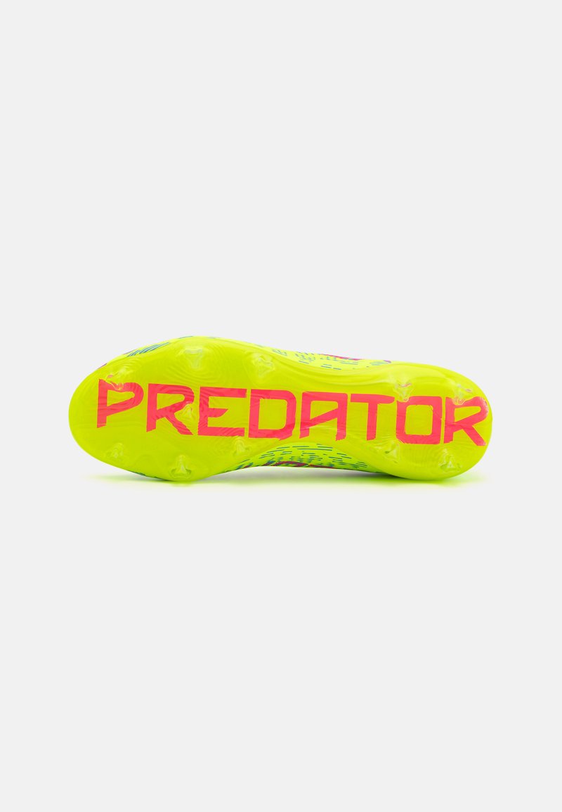 Suela de botas de fútbol Predator en amarillo brillante con texto "PREDATOR" en rosa, que presenta tacos de agarre texturizados para tracción y optimización de habilidades.