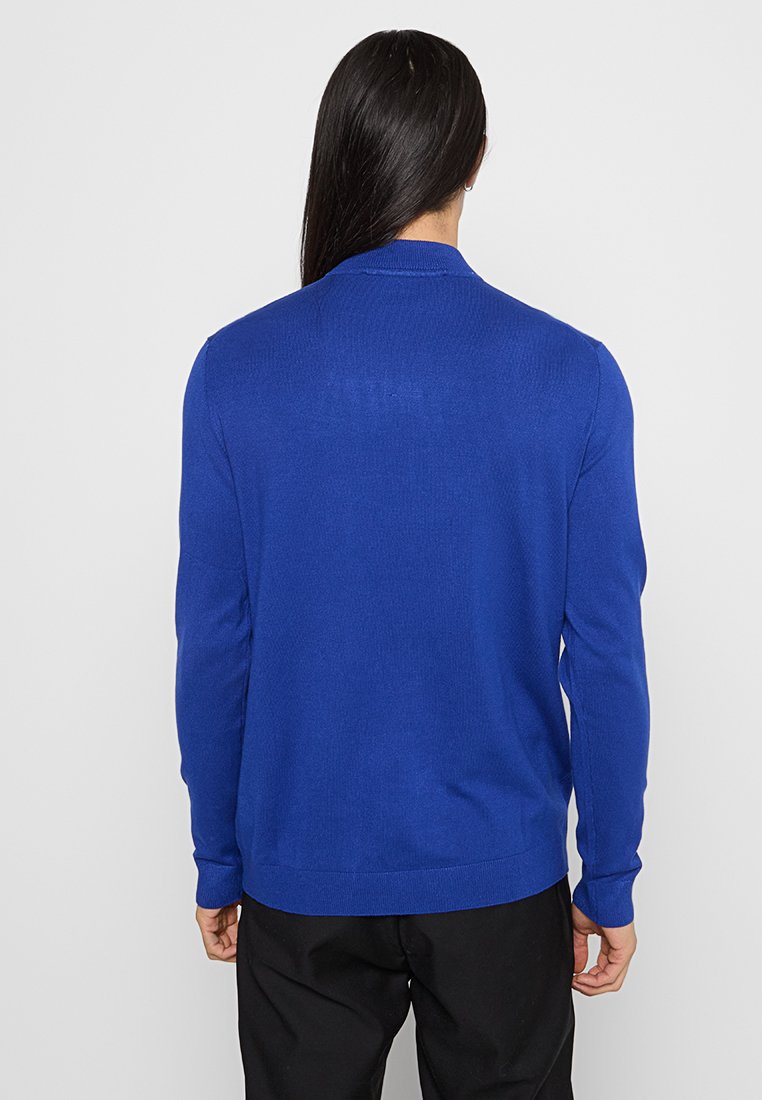 Königsblauer Strickpullover mit langen Ärmeln, rundem Halsausschnitt und gerippten Bündchen und Saum, mit einer glatten Textur.