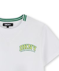 Camiseta de algodón blanca con cuello en V, que presenta un collar a rayas verde y blanco y un logo de "DKNY" en color amarillo-verde con el texto "EL UNIFORME OFICIAL DE NUEVA YORK."