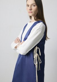 Rochie din satin de culoare bleumarin, cu decolteu în V, ce dispune de un cordon la talie cu șnururi de culoare crem și o siluetă stratificată.