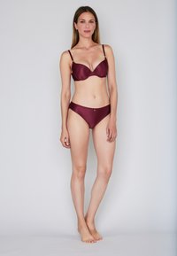 Set bikini marrone con design testurizzato a coste. Il top ha ferretto e spalline regolabili; il bottom ha un taglio classico.