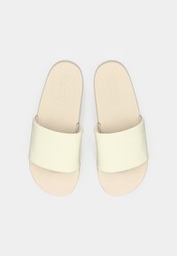 Δύο ανοιχτά κίτρινα σανδάλια με φαρδιά υφασμάτινη λουρίδα και ανατομική φόρμα σόλας, με το λογότυπο adidas ανάγλυφα στο πέλμα.