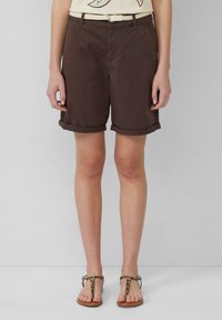 Bruine katoen shorts met opgerolde omslagen, gecombineerd met een beige gevlochten riem en sandalen met luipaardprint. Eenvoudig ontwerp, geschikt voor casual kleding.