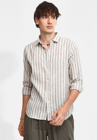 Camicia a maniche lunghe leggera a righe nei toni beige e grigi, con colletto, maniche arrotolate fino ai gomiti e bottoni bianchi.
