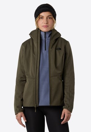Veste soft-shell vert olive avec un col haut, fermeture éclair noire et poches zippées, superposée à un haut en polaire bleu clair.