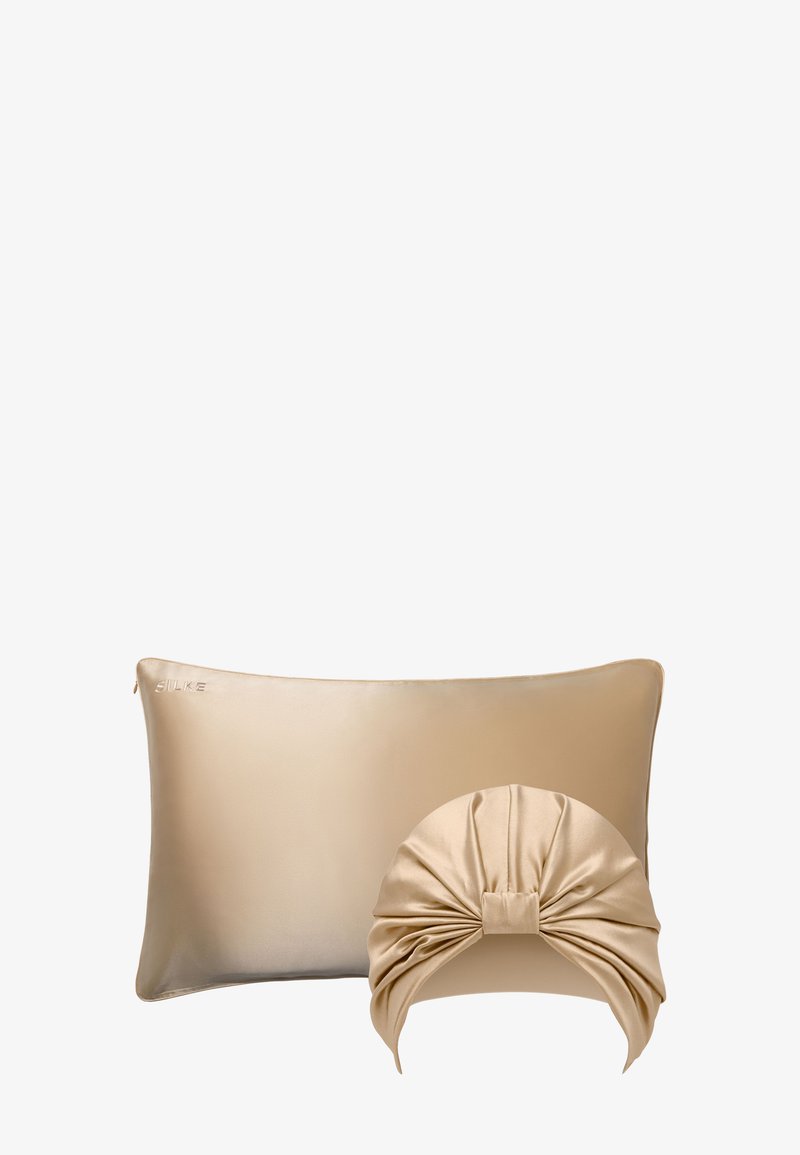 Funda de almohada de satén en beige con una textura suave, acompañada de una diadema de satén a juego que presenta un diseño trenzado en la parte superior.