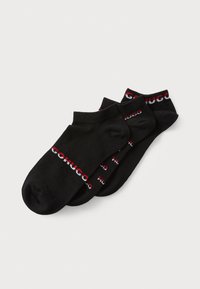 Schwarze Knöchelsocken aus weichem Material. Mit einem kontrastierenden Logo-Band in Rot und Weiß, auf dem der Text 'HUGO' wiederholt ist. Enthält drei Paar.