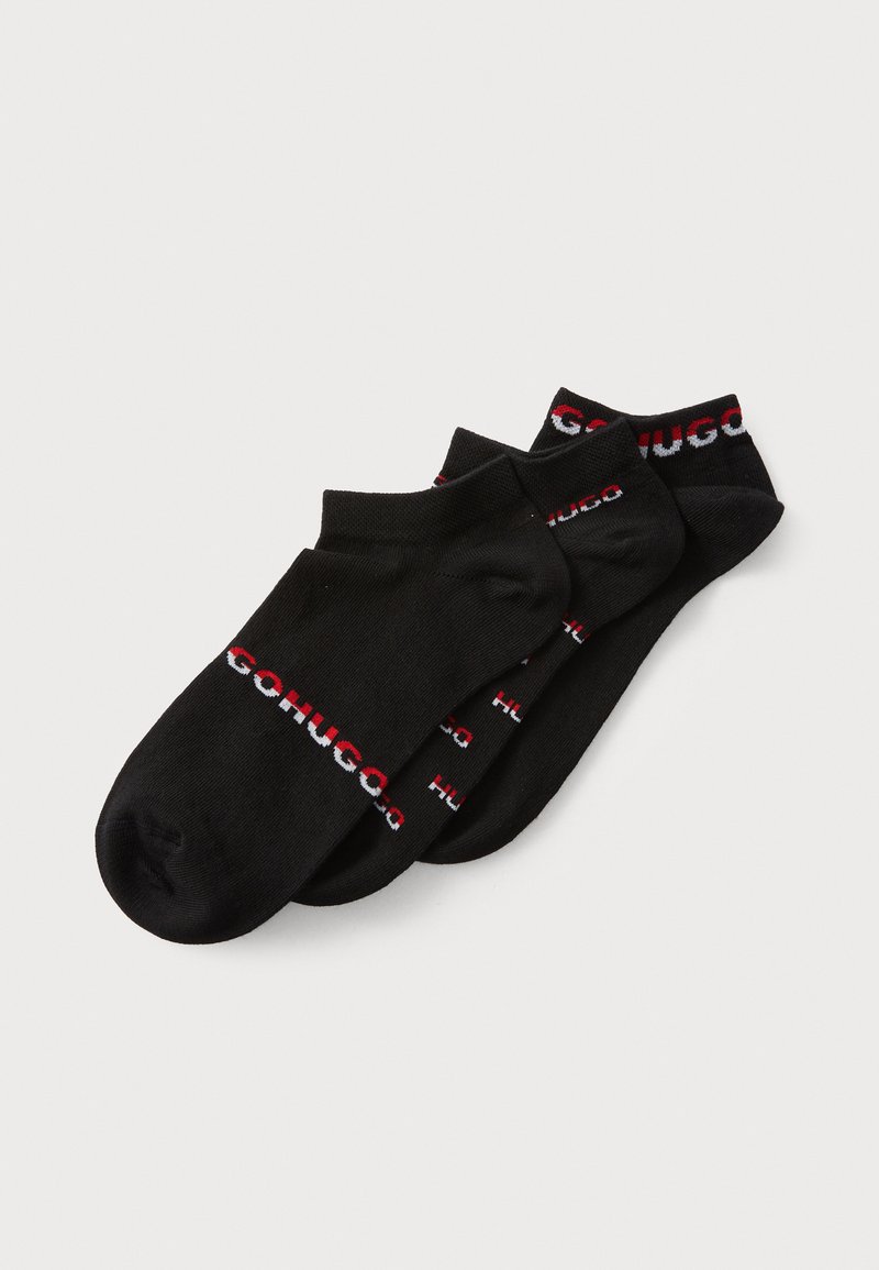 Schwarze Knöchelsocken aus weichem Material. Mit einem kontrastierenden Logo-Band in Rot und Weiß, auf dem der Text 'HUGO' wiederholt ist. Enthält drei Paar.