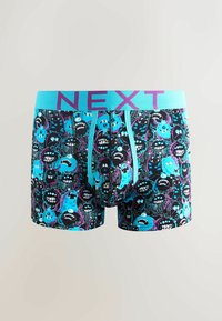Bañadores de boxeo con una tela negra decorada con gráficos coloridos de monstruos en azul, púrpura y verde azulado. Cintura elástica con la etiqueta "NEXT" en púrpura.