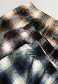 Plaid patterned fabric in three colors: tan with dark blue, burgundy with cream, and navy with light blue. Soft texture and elastic waistband.