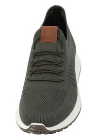 Zielone dzianinowe sneakersy z teksturowaną cholewką, brązowym skórzanym akcentem na języku i białą podeszwą środkową. Posiadają elastyczne sznurowadła i zaokrąglony czubek.